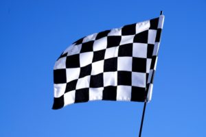 the checkered flag waving at a track that uses rain insurance for motorsports