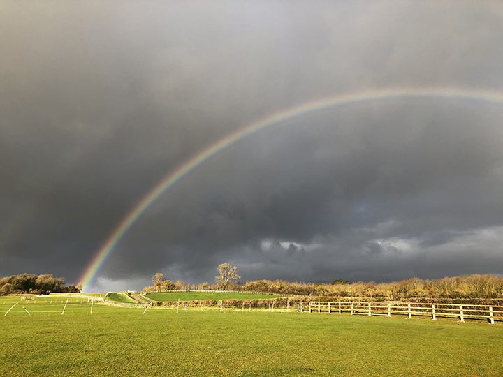 rainbow over countryside to illustrate happy ending for how parametric rain insurance works