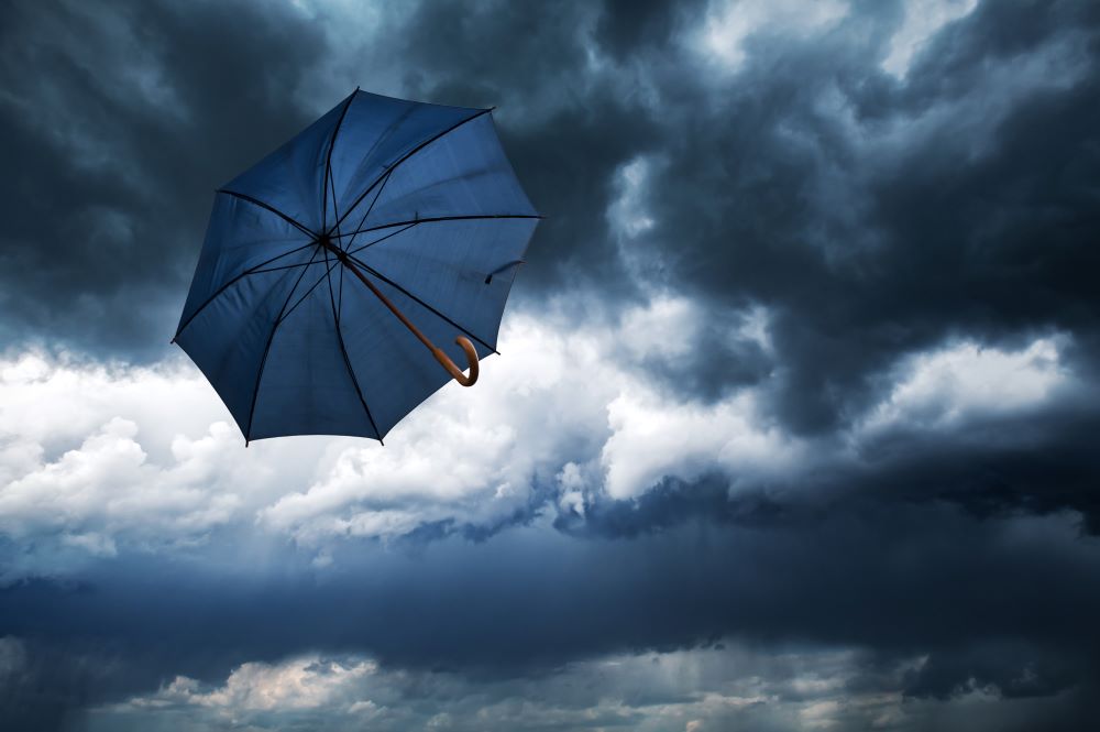 flying-blue-umbrella-and-cloudy-rainy-sky symbolizing need for vortex hurricane insurance