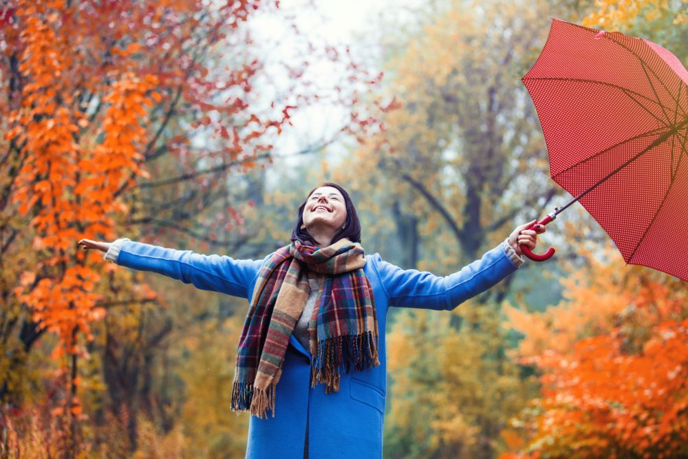 brunette girl with umbrella feeling better about rainy day because she has proper event risk management