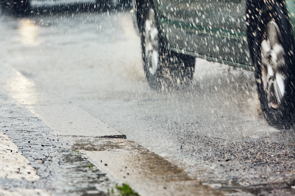 car splashing water in gutter to represent rainfall for weather insurance claim