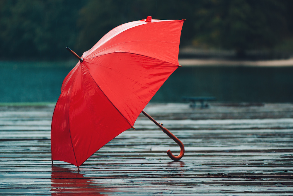 red umbrella on a wet surface representing rain insurance vs event insurance